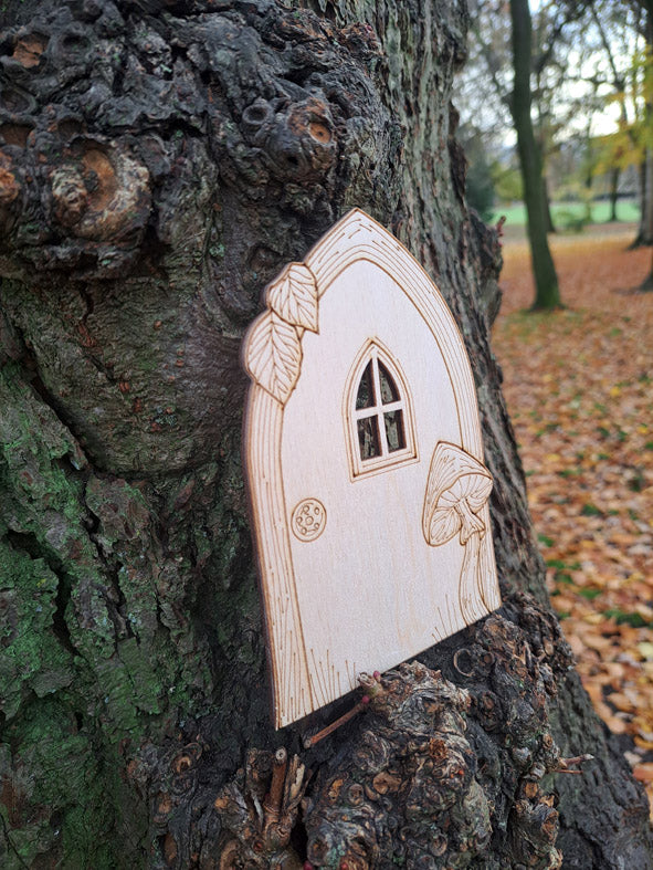 Holztür zum Kinderbuch Der kleine Zauberer Pfifferling an einem Baumstamm